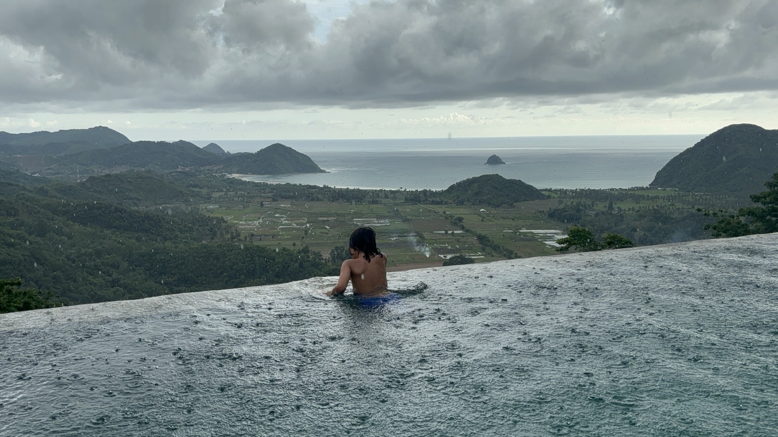 A child in a rain-covered infinity pool in Lombok