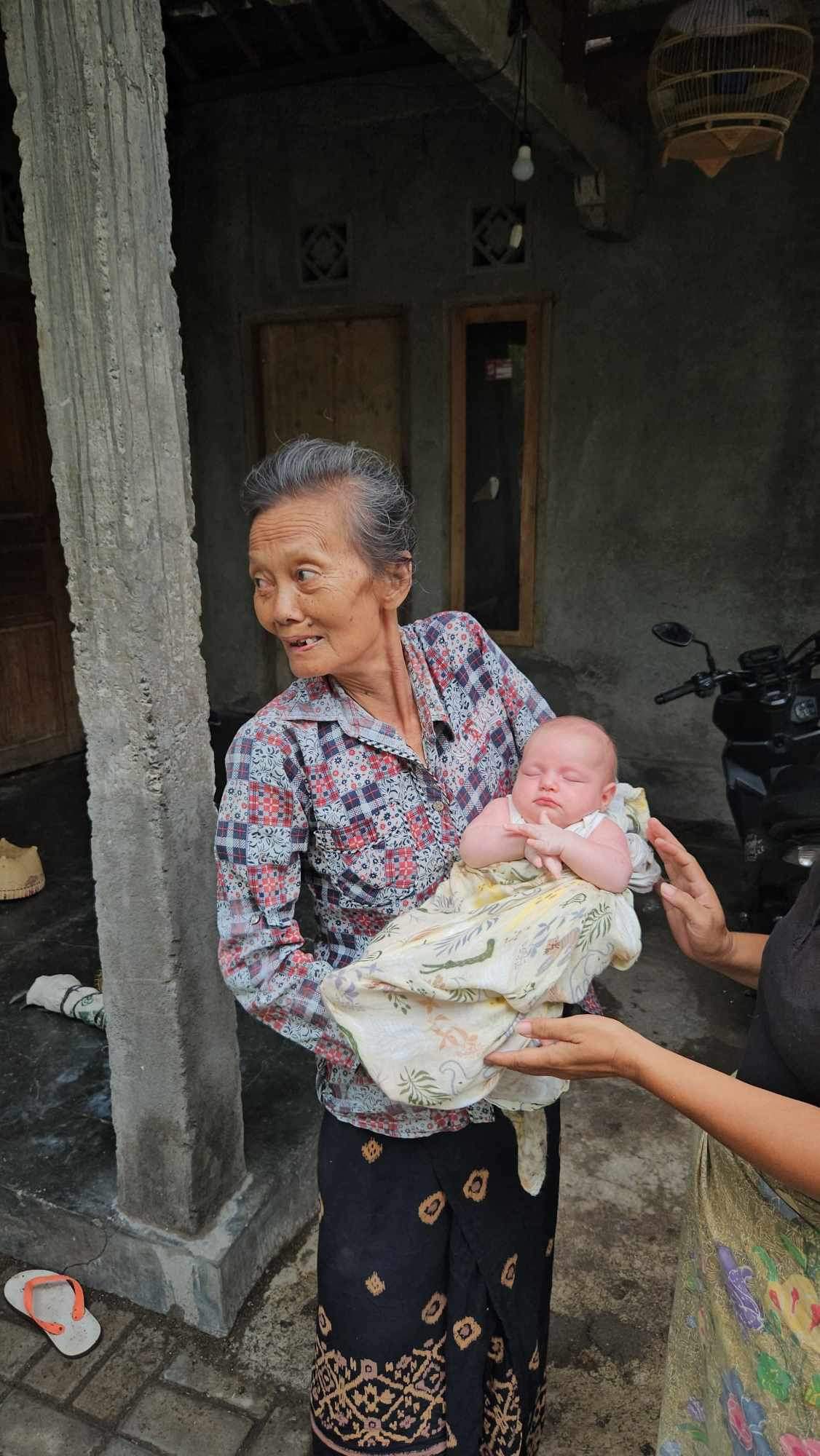 A grandmother in Lombok holding the sleeping baby